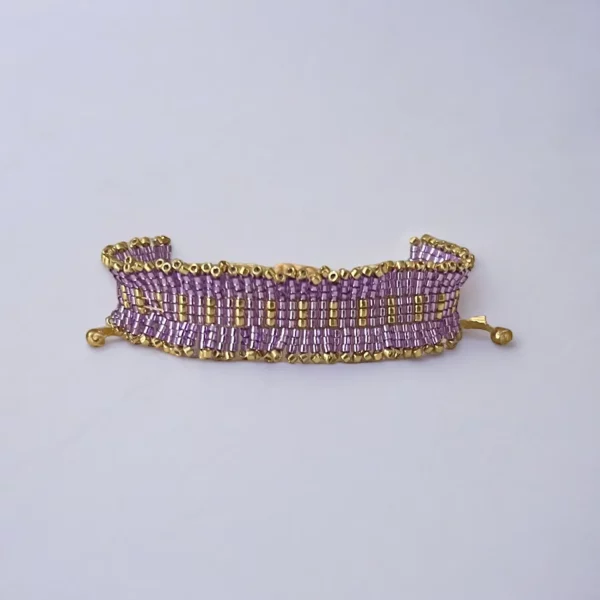 Gold and purple beaded bracelet on white background.
