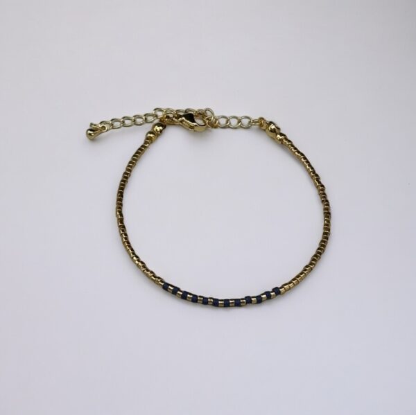 Gold bracelet with blue accents on white background.