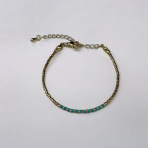 Gold bracelet with turquoise beads on white background.