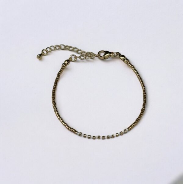 Gold bracelet with adjustable chain on white background.