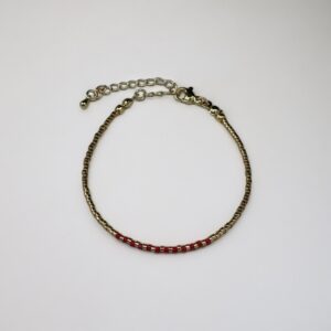 Gold bracelet with red beads on white background.