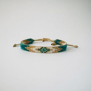 Beaded turquoise and gold bracelet on white background.