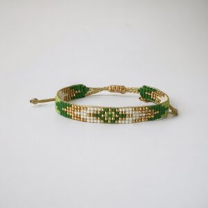 Green and gold friendship bracelet on white background.