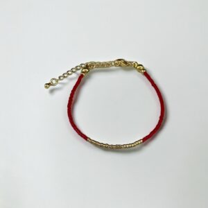Red bracelet with gold accents on white background.