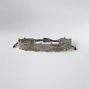 Beaded adjustable bracelet with gold accents on white.