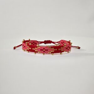 Red beaded bracelet with gold accents on white.