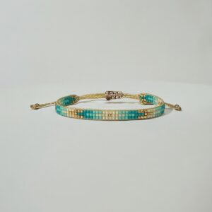 Turquoise beaded gold bracelet on white background.