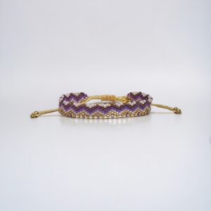 Purple beaded bracelet with gold accents on white background.